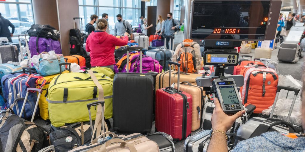 Traveler weighing luggage at an airport check-in.