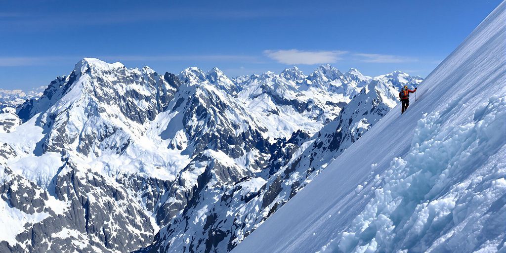 Climber ascending snow-capped mountain in Alaska.